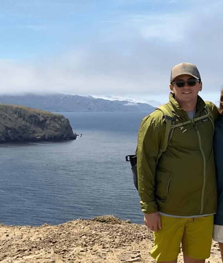 Lior on a cliff above the ocean in a green jacket